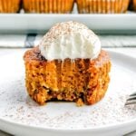 mini pumpkin pie with graham cracker crust topped with whipped cream with a bite taken out of it.