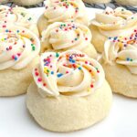 thumbprint cookies with almond buttercream icing on a white platter.