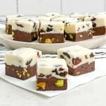 squares of cherry fudge on a white napkin in front of a wooden plate with more squares of fudge.