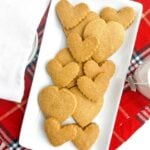 baked brown sugar shortbread cut out cookies on a white platter on a red plaid scarf.