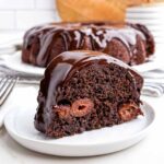 piece of chocolate cherry bundt cake on a white plate.