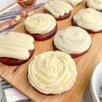 cream cheese frosting piped onto red velvet cookies.