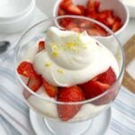 strawberries and cream in a clear coupe glass.