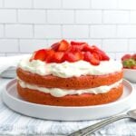 strawberry whipped cream cake on a white plat.