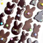 chocolate cut out bunny cookies decorated with M&Ms and sprinkles on white countertop.