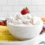 strawberry cool whip fruit dip in a white bowl on a fruit platter.