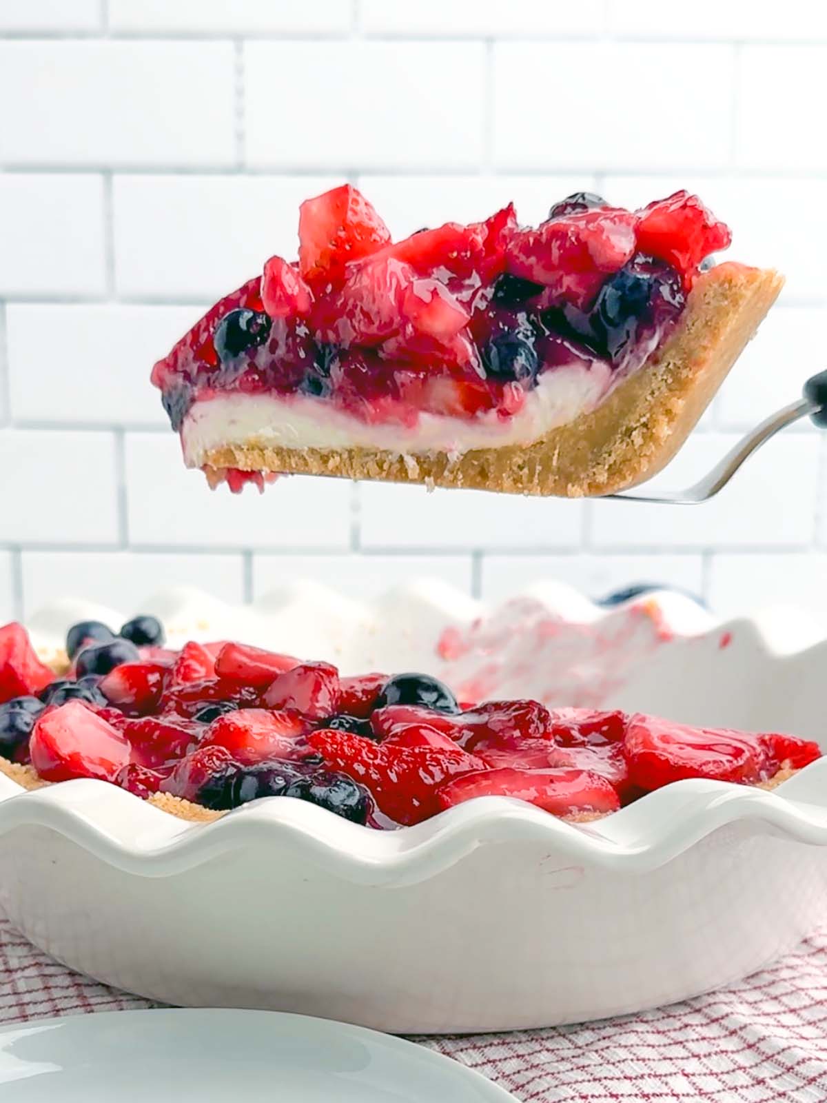 pie server holding up a piece of strawberry blueberry pie.