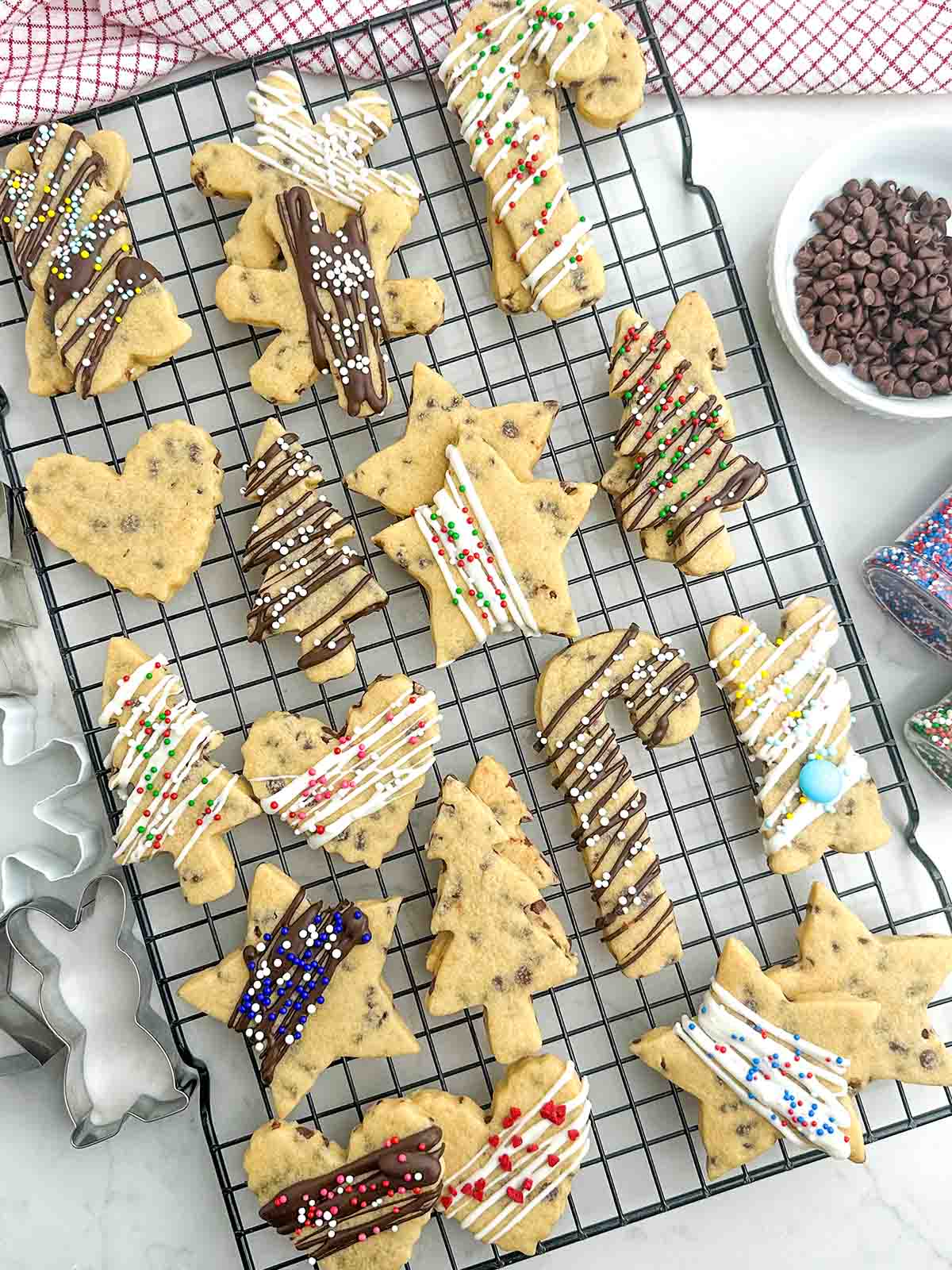 plain and decorated chocolate chip cutout cookies on a baking rack.