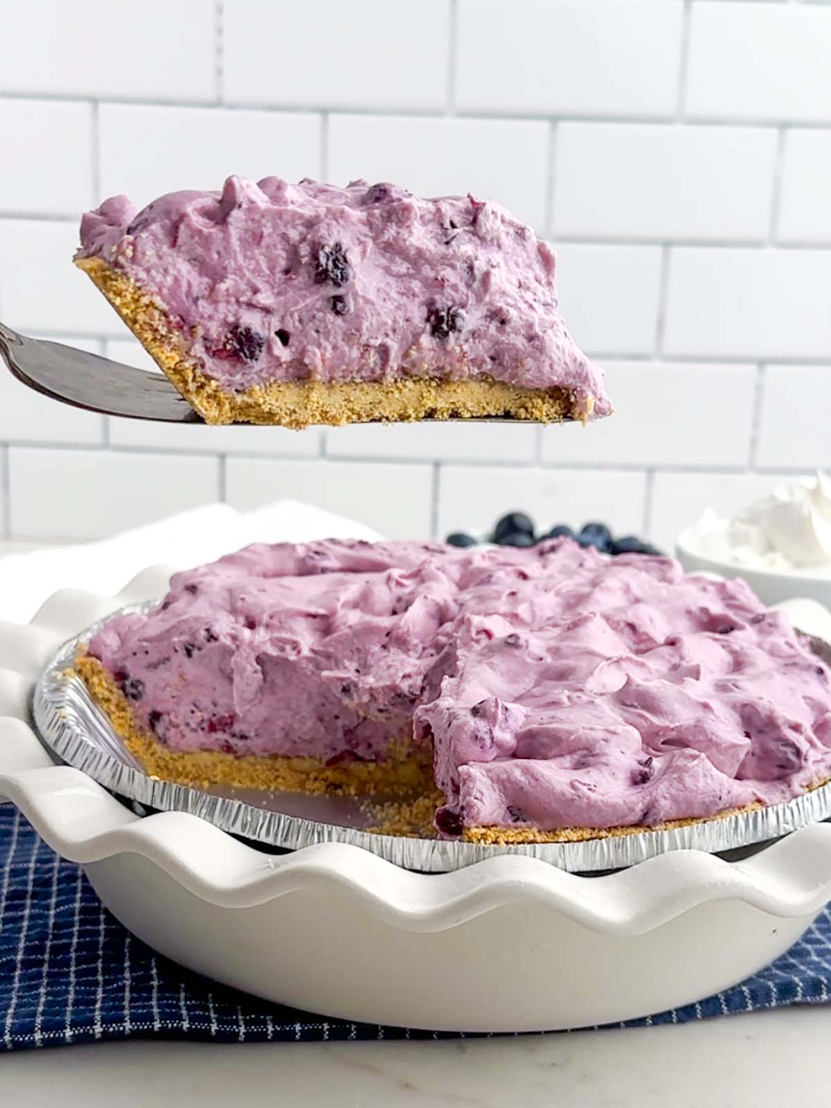 pie server lifting a piece of blueberry cream pie.