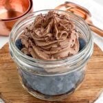 chocolate whipped cream on top of blueberries in a mason jar.