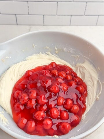 cherry pie filling in a bowl of whipped cream cheese mixture.