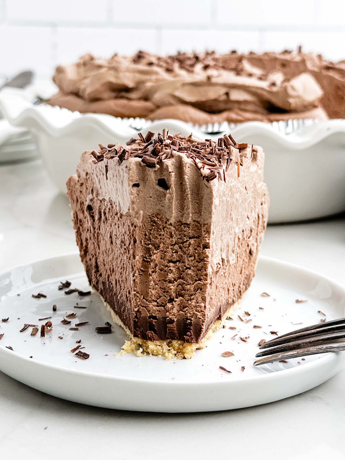 front view of a piece of chocolate mousse pie in a graham cracker crust with a bite taken out.