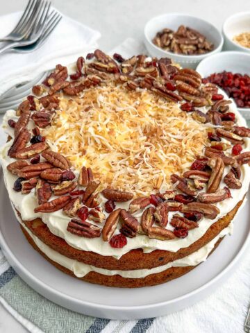 hummingbird cake topped with cream cheese frosting, toasted pecans, dried cranberries, and toasted coconut.