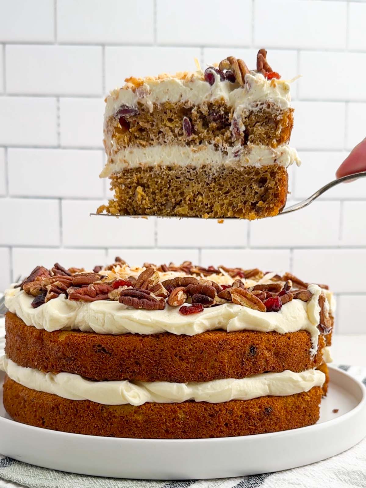cake server holding a slice of hummingbird cake over the rest of the cake.