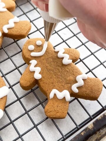 hand piping icing onto a gingerbread man.