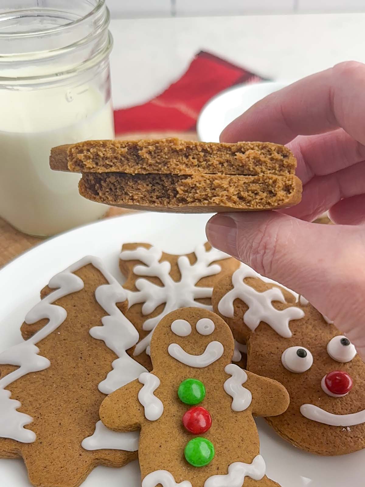 hand holding up a gingerbread cookie broken in half.