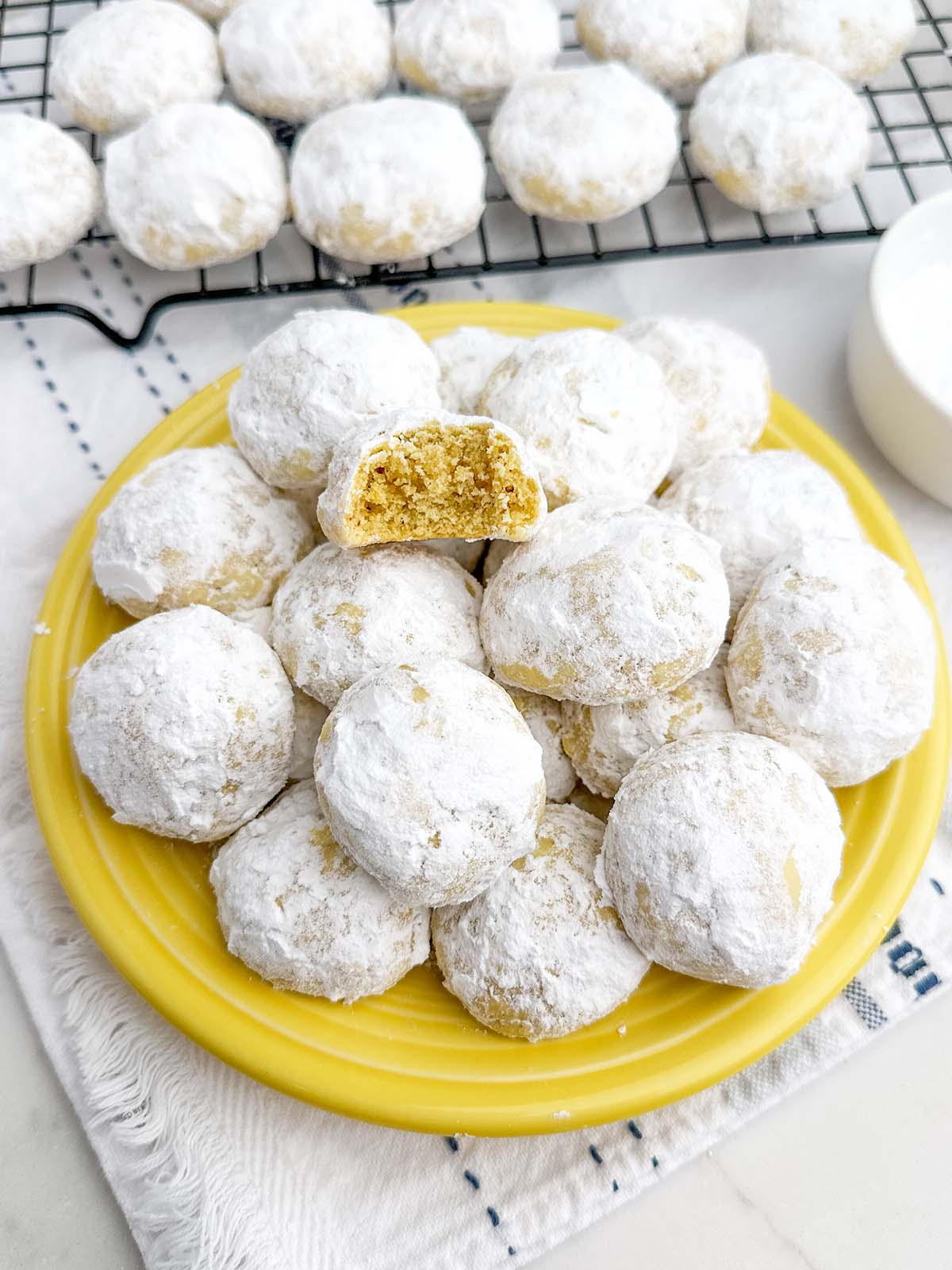 lemon snowball cookies on a yellow plate.