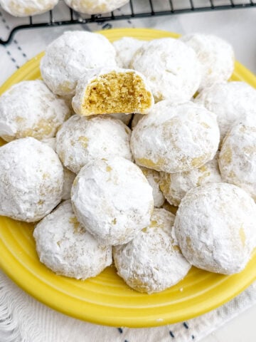 lemon snowball cookies on a yellow plate.