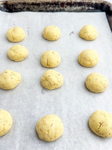 lemon snowball cookies on a parchment lined baking sheet.